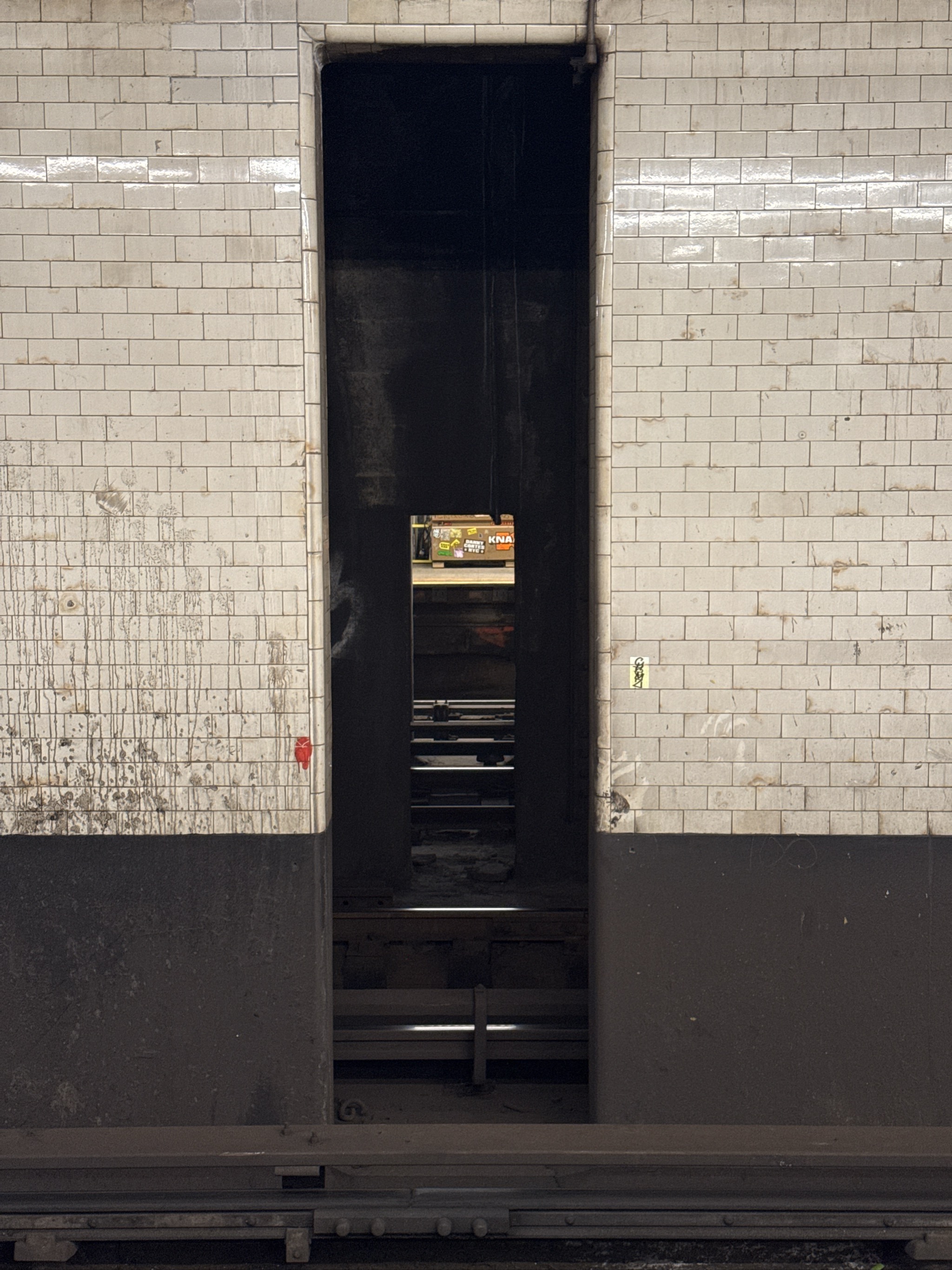 Narrow subway entrance with stairs leading down between tiled walls