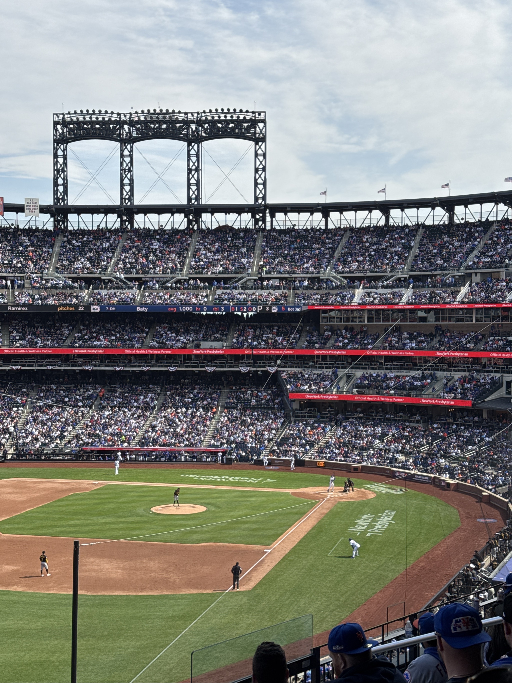 Baseball game at stadium with distinctive bridge structure behind outfield