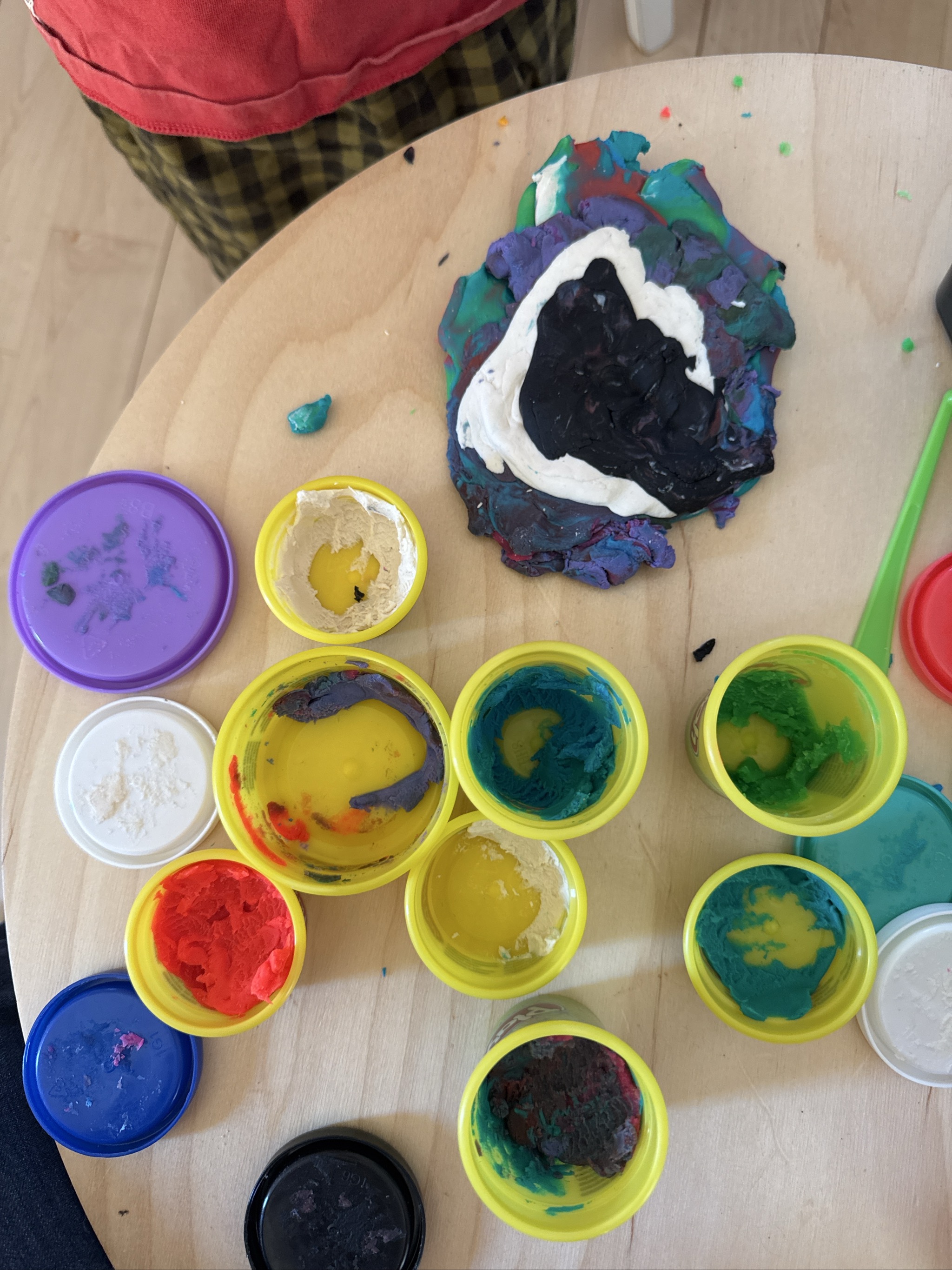 Colorful paint containers and mixed paint creation on wooden table