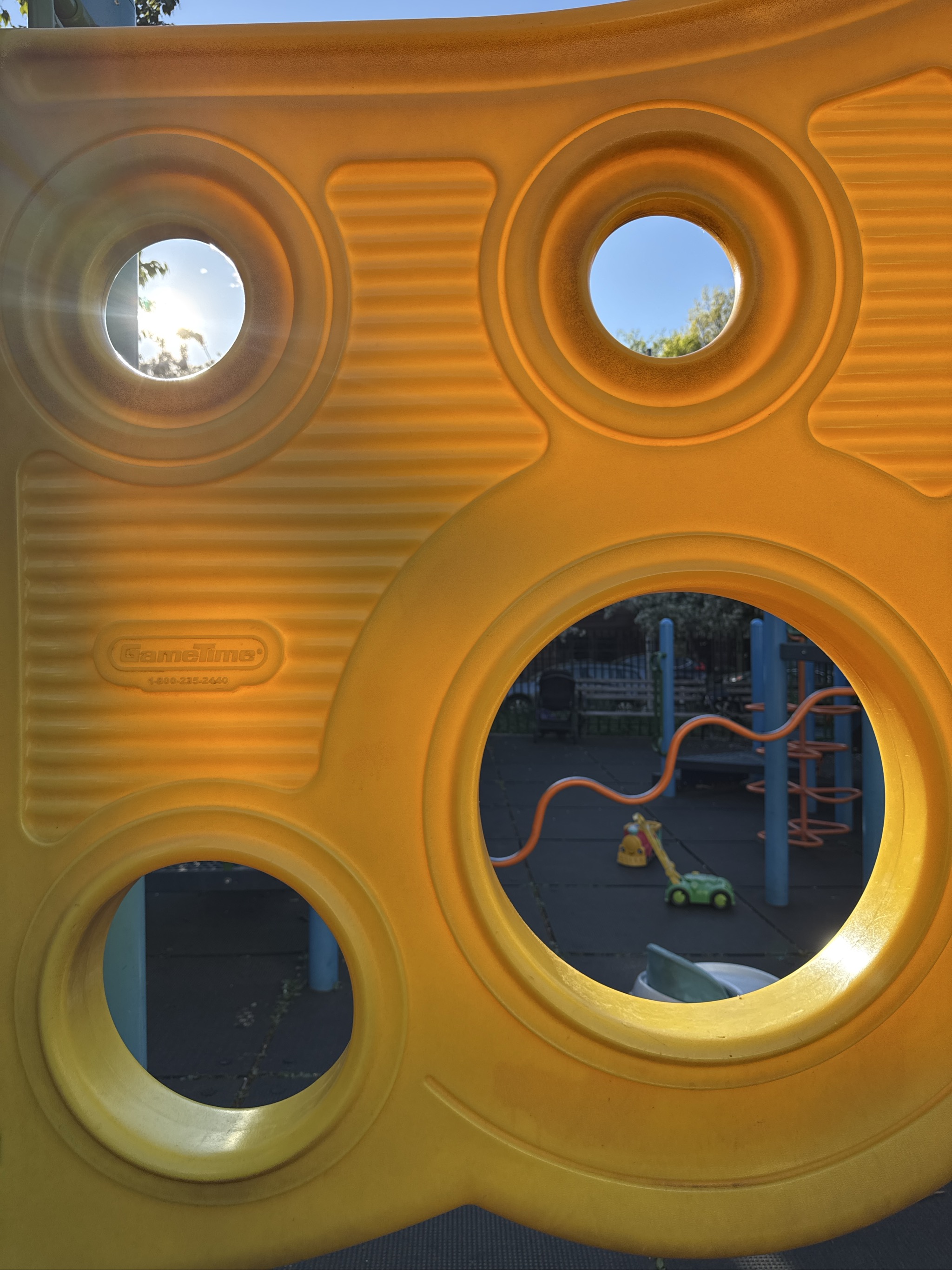 Yellow playground structure with circular windows showing playground equipment inside.