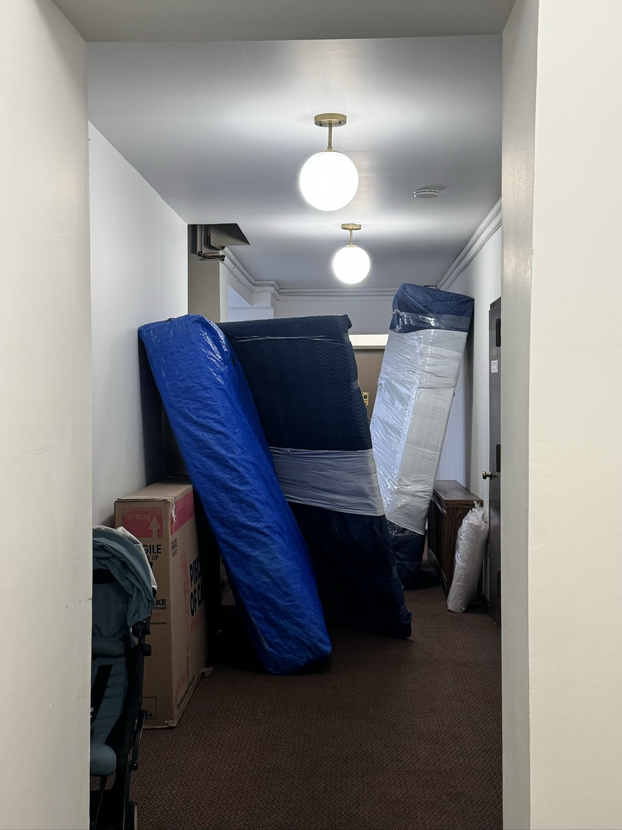 Hallway packed with wrapped furniture and moving boxes during relocation.