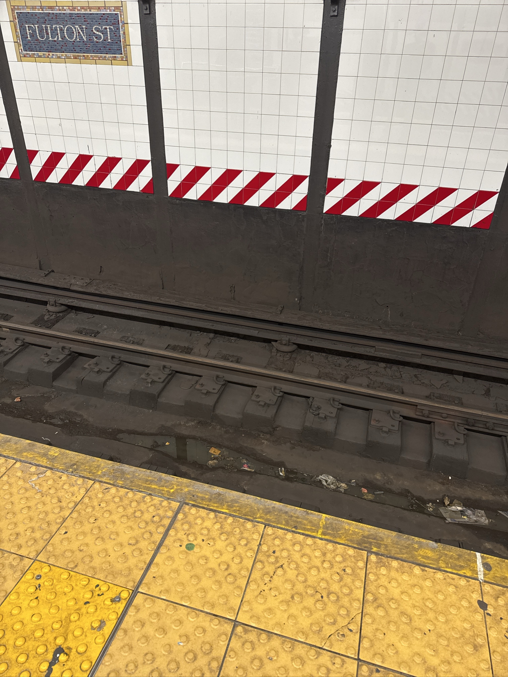Fulton Street subway platform with tracks and safety striping.