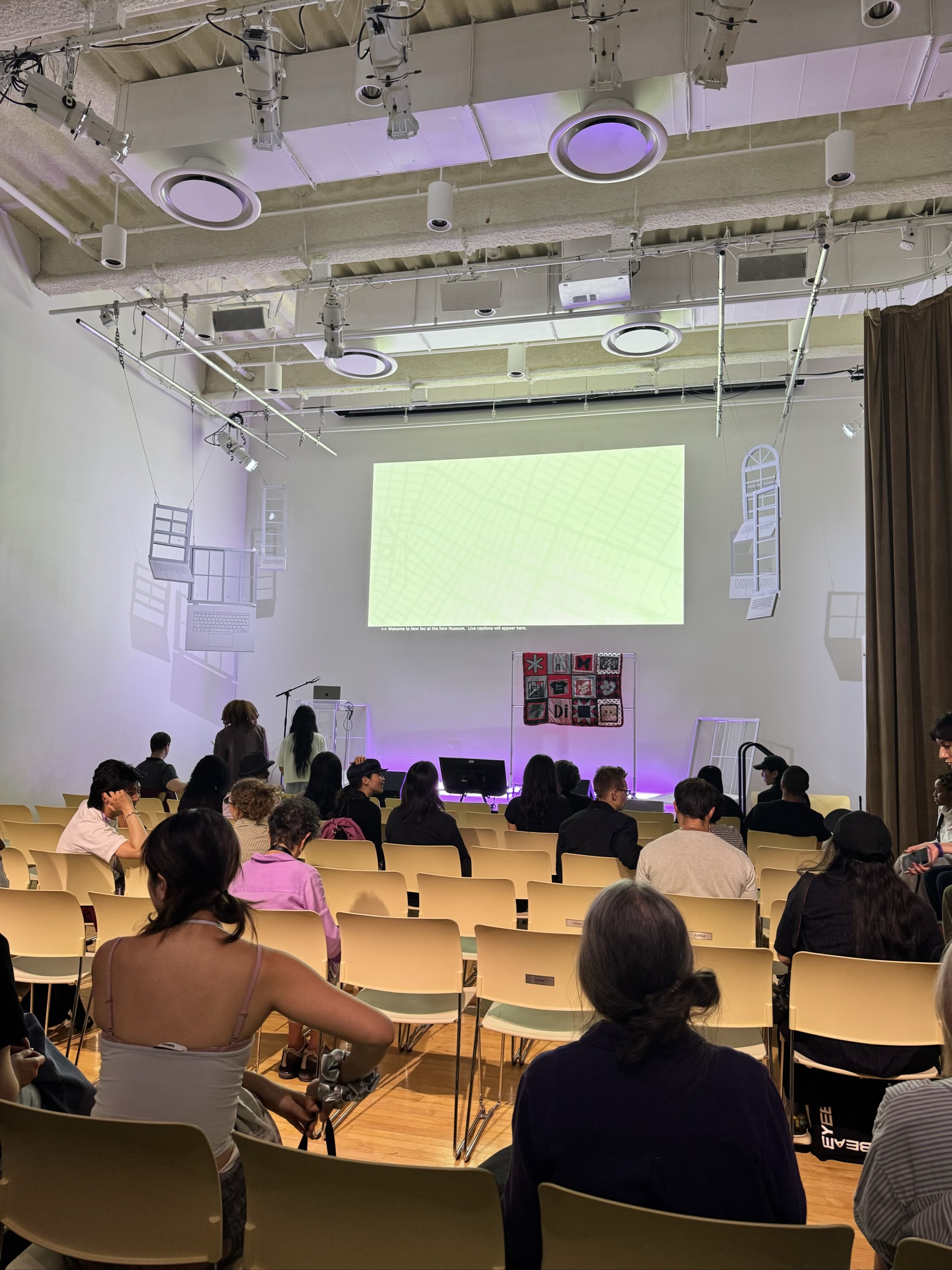 Audience watching presentation in modern lecture hall with purple lighting.