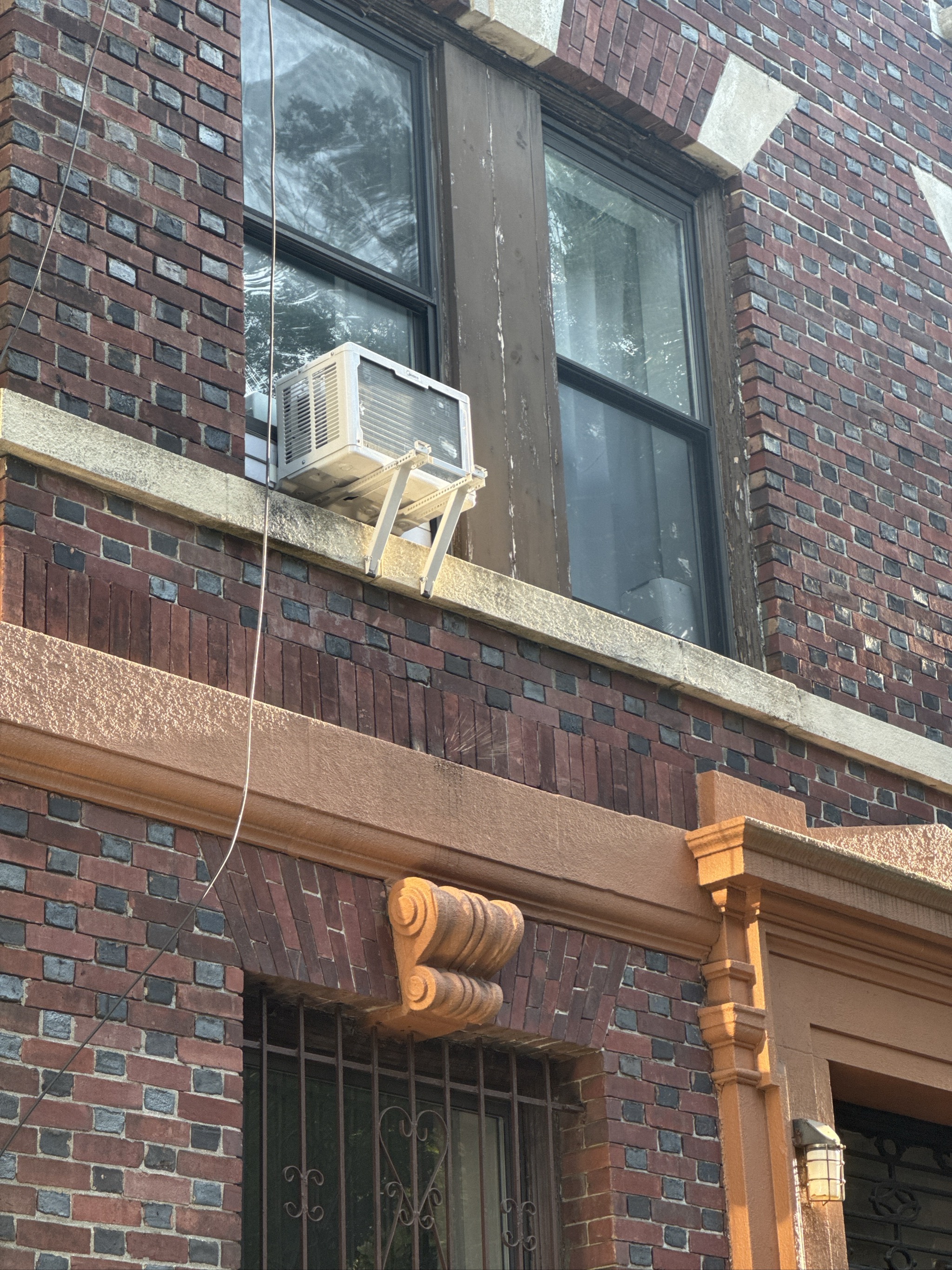 Brick building with window air conditioner and ornate entrance details.
